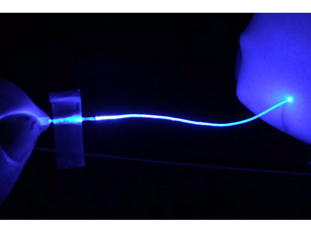A blue glowing fiber in darkness. The fiber is held by finger and seems to light up with it touches another hand.