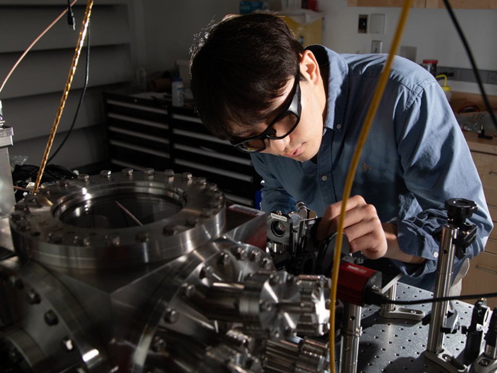 Dongchel Shin, looking closely and working on a scientific instrument.