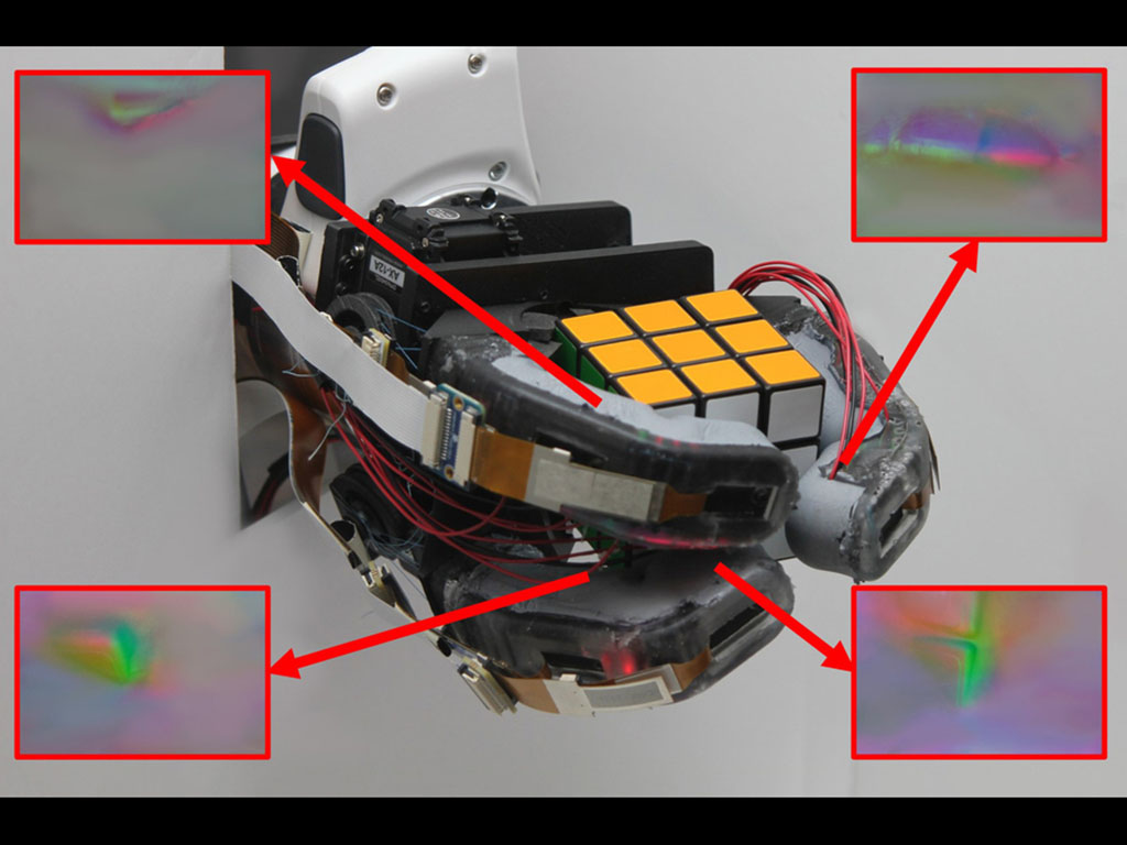 Photo shows a robotic hand holding a Rubik's Cube. Four insets shows colorful renderings of the hand’s sensors. 