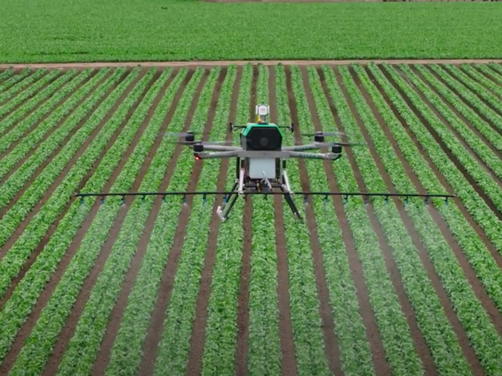 Drone built by MIT alum safely sprays fertilizer over green field