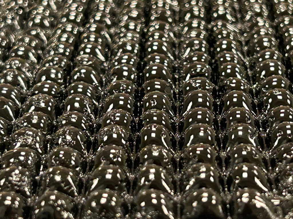 A close-up of a new, black, liquid like origami-inspired hydrogel material, designed by MIT engineers, that swells to absorb water from the air.