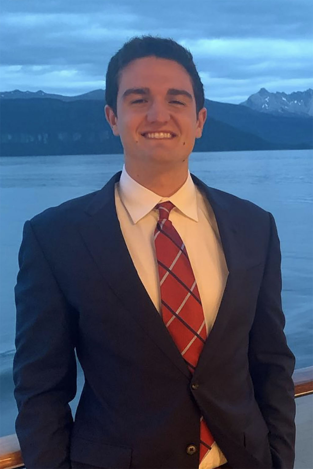 Portrait of Brooker Schelhass in front of water in a suit