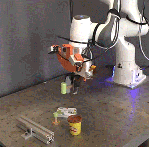 The policy composition technique the researchers developed can be used to effectively teach a robot to use tools even when objects are placed around it to try and distract it from its task, as seen here.